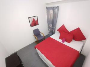 a bedroom with a red and white bed and a chair at Sunset Executive Lodge in Boksburg