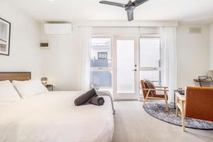 a white bedroom with a bed and a desk and a ceiling fan at Walk to everything Carlton has to offer in Melbourne