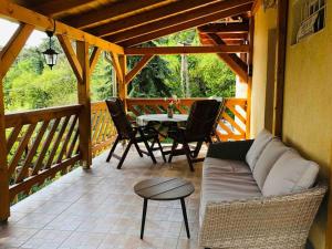 a porch with a couch and a table and chairs at Kis Pele Nyaralóház in Balatongyörök