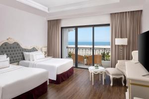 a hotel room with two beds and a balcony at Melia Vinpearl Cua Hoi Beach Resort in Cửa Lò