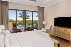 ein Hotelzimmer mit einem großen Bett und einem Flachbild-TV in der Unterkunft Melia Vinpearl Cua Hoi Beach Resort in Cửa Lô