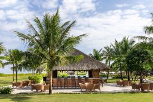 a pavilion with chairs and a palm tree at Melia Vinpearl Cua Hoi Beach Resort in Cửa Lò