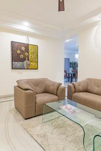 a living room with two brown couches and a glass table at Luxury Suites by Athome in Kondapur
