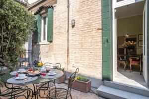 eine Außenterrasse mit 2 Tischen und Stühlen und ein Gebäude in der Unterkunft Ca' Margherita Secret Garden in Venedig