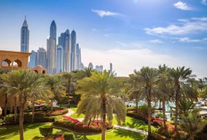a park with palm trees and a city in the background at One&Only Royal Mirage Resort Dubai at Jumeirah Beach in Dubai
