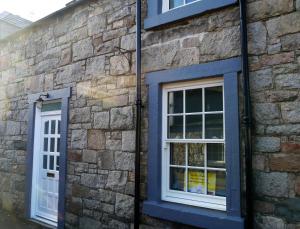 2 ventanas en un edificio de piedra con adornos azules en Stroan en New Galloway