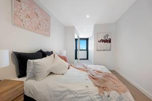 Schlafzimmer mit einem Bett mit weißer Bettwäsche und Kissen in der Unterkunft Location Style Comfort and Beauty on Swan in Melbourne