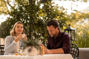 un hombre y una mujer sentados en una mesa bebiendo café en Hotel Hanswirt, en Rablà