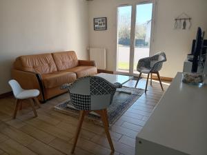een woonkamer met een bank en 2 stoelen bij Sérénité à la mer in Concarneau