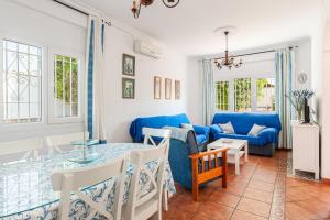 ein Wohnzimmer mit einem Tisch und einem blauen Sofa in der Unterkunft Chalet Fuente4 piscina común famila in Conil de la Frontera