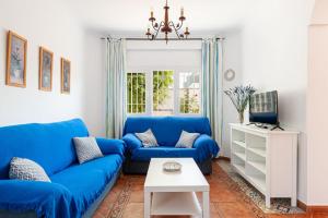 ein Wohnzimmer mit einem blauen Sofa und einem Tisch in der Unterkunft Chalet Fuente4 piscina común famila in Conil de la Frontera