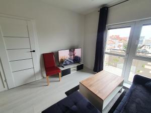 salon z telewizorem i czerwonym krzesłem w obiekcie Apartament Business Sienkiewicza w mieście Leszno