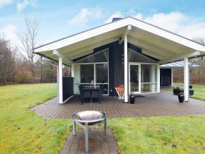 a covered patio with a table and a grill at 6 person holiday home in H jslev in Højslev