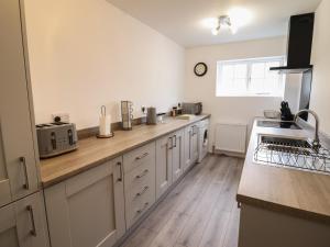 a kitchen with white cabinets and a wooden counter top at The Old Coach House in Conwy