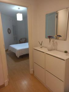 een badkamer met een dressoir met een spiegel en een bed bij Cantabrico playa Grupo AC Gestion in Cádiz