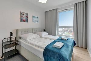 1 dormitorio con 1 cama con manta azul y ventana en Viewpoint - Bastion Wałowa by Grand Apartments en Gdansk
