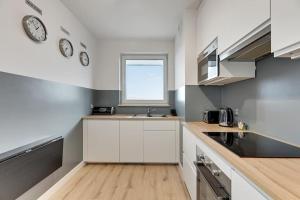 a kitchen with white cabinets and a clock on the wall at Viewpoint - Bastion Wałowa by Grand Apartments in Gdańsk