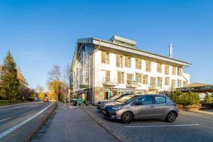 two cars parked in a parking lot in front of a building at Aparthotel Belveder in Vysoke Tatry - Tatranska Lomnica.