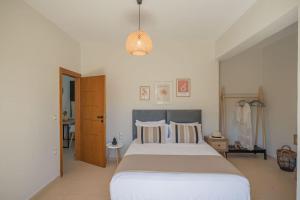 een slaapkamer met een groot bed en een hanglamp bij Summer Blue Apartments Chania in Chania