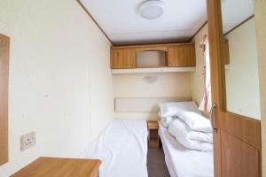 Cette petite chambre comprend deux lits et une table. dans l'établissement 8 Berth Caravan For Hire At California Cliffs Holiday Park In Norfolk Ref 50046l, à Great Yarmouth