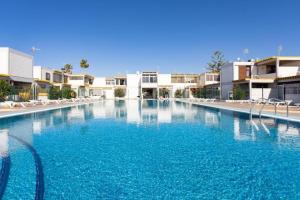 a large swimming pool with blue water in front of buildings at Papagayo Beach Apartments in Arona