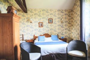 a bedroom with a bed with blue pillows and two chairs at Logis Auberge le centre poitou in Coulombiers