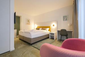 a bedroom with a large bed and a pink chair at Boutique Hotel Piazza Grande in Locarno