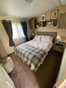 a bedroom with a bed with a plaid blanket at Superb luxury two bed caravan, Todber Valley Holiday Park, sleeps six in Gisburn