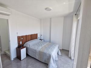 Habitación blanca con cama y mesita de noche en Beach house los alcazares, en Los Alcázares