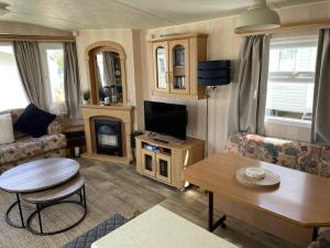 uma sala de estar com uma televisão, um sofá e uma mesa em Charming 6 birth caravan in skegness em Skegness