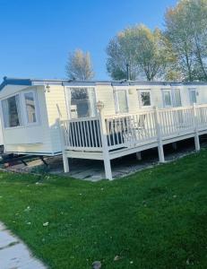a mobile home with a porch and a white railing at Charming 6 birth caravan in skegness in Skegness