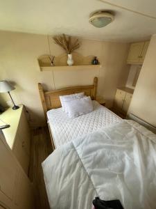 a small bedroom with a bed and a nightstand with a bed sidx sidx sidx at Charming 6 birth caravan in skegness in Skegness