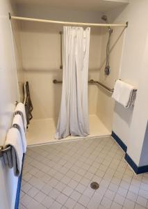 ステートカレッジにあるNittany Budget Motelのバスルーム(白いシャワーカーテン付きのシャワー付)が備わります。