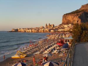 a beach with umbrellas and people on the beach at B&b Cefalù in Cefalù