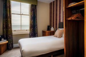 1 dormitorio con cama y ventana con vistas al océano en Esplanade Hotel Llandudno, en Llandudno