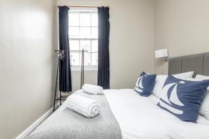 ein Bett mit blauen und weißen Kissen und einem Fenster in der Unterkunft Market Street Apartment Sleeps 6 in St Andrews