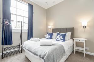 Schlafzimmer mit einem Bett mit blauen und weißen Kissen in der Unterkunft Market Street Apartment Sleeps 6 in St Andrews