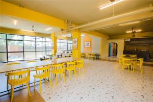 uma cafetaria com mesas e cadeiras numa sala com paredes amarelas em Covie Bannergatta 185 em Bangalore