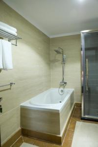 a bath tub in a bathroom with a shower at Hola Hotel in Al Jubail