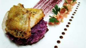 um prato branco com um pedaço de comida com arroz roxo em Hotel Zamek Ryn em Ryn