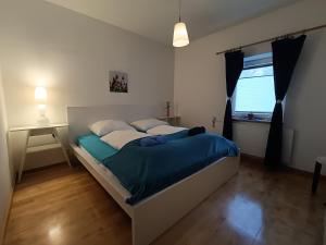 um quarto com uma cama com lençóis azuis e uma janela em Stylish & Spacious Apartment with Patio em Stams