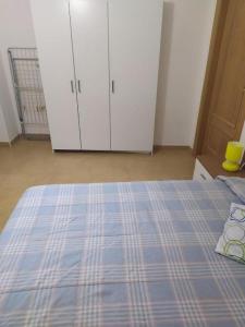 1 dormitorio con 1 cama con manta a cuadros y armarios en La Cocineta - Crabetas, en Alquézar