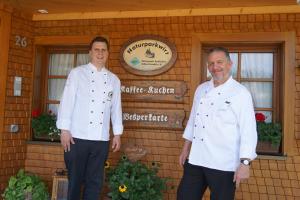 two men in white shirts standing in front of a building at Naturparkhotel Schwarzwaldhaus in Bernau im Schwarzwald