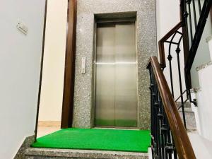 a stairway with a green floor in front of a elevator at Olive Service Apartments - DLF Cyber City in Gurgaon