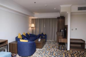 een woonkamer met een blauwe bank in een hotelkamer bij Hola Hotel in Al Jubail