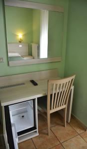 una scrivania con specchio e sedia in camera di Hotel Aquila a Scoppito