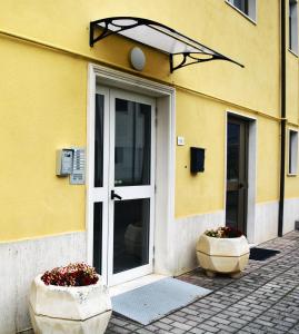 un edificio giallo con una porta e due vasi di fiori di Hotel Aquila a Scoppito