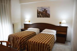 una camera d'albergo con due letti e una foto a parete di Hotel Aquila a Scoppito