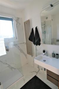 La salle de bains blanche est pourvue d'une douche et d'un lavabo. dans l'établissement Appartamento - PUNTA SABBIONI, à Cavallino-Treporti