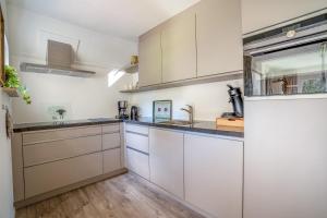Una cocina con gabinetes blancos y electrodomésticos de acero inoxidable. en Villapark Kamperfoelie 91, en De Koog